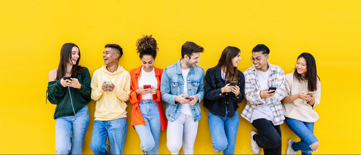 multiracial group laughing while looking on phones